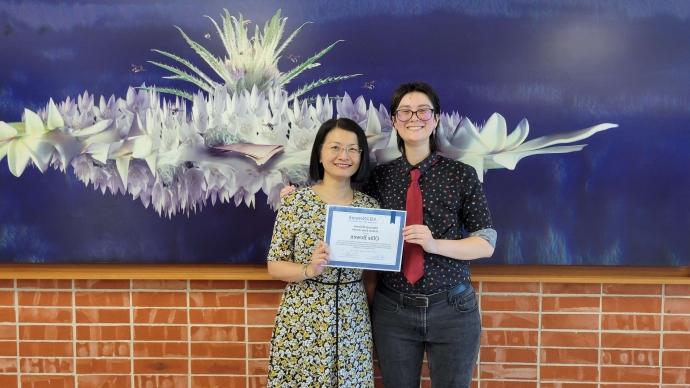 A student and a 教师 member pose for a photo with an award.